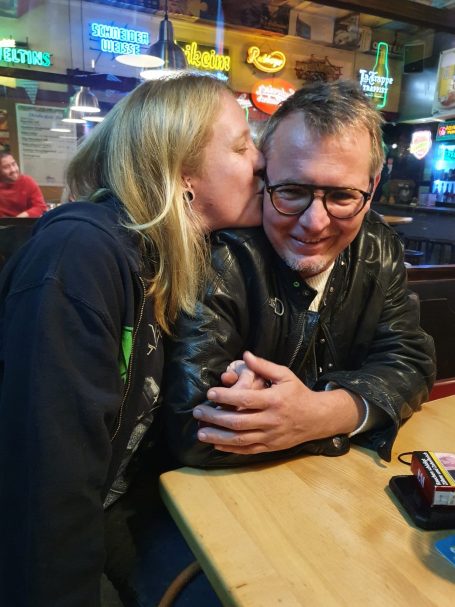 Frau gibt einem Mann einen Kuss auf die Wange in einer gemütlichen Bar.